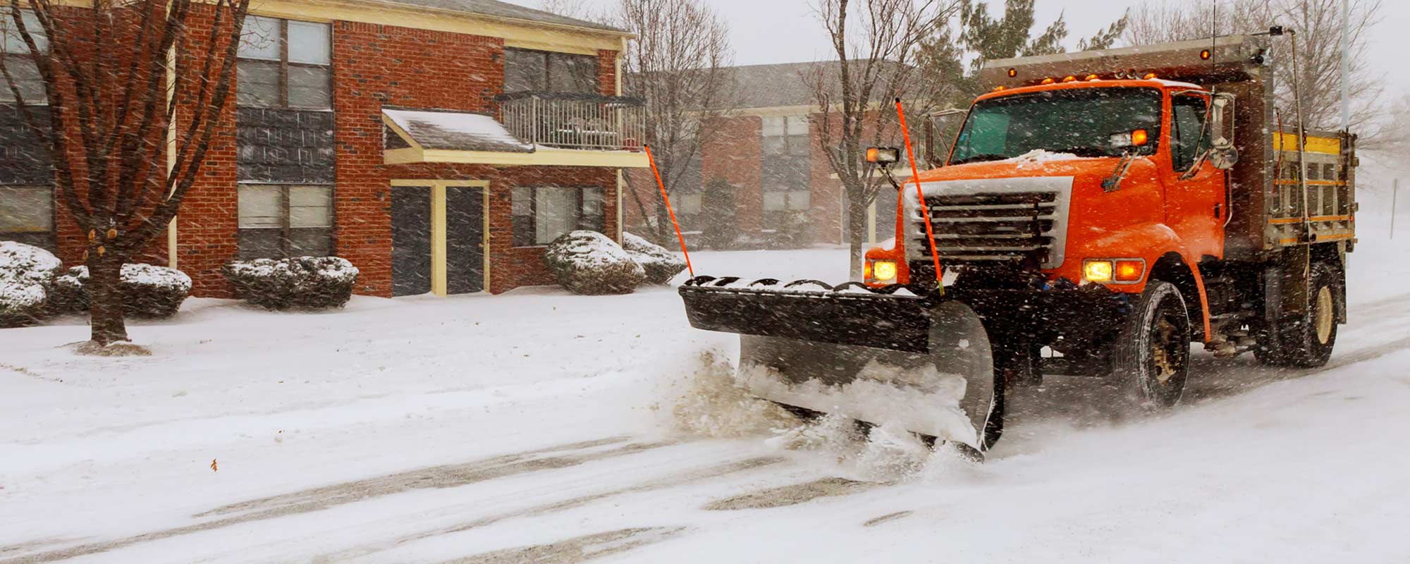snow plow clearing residential street in snow storm
